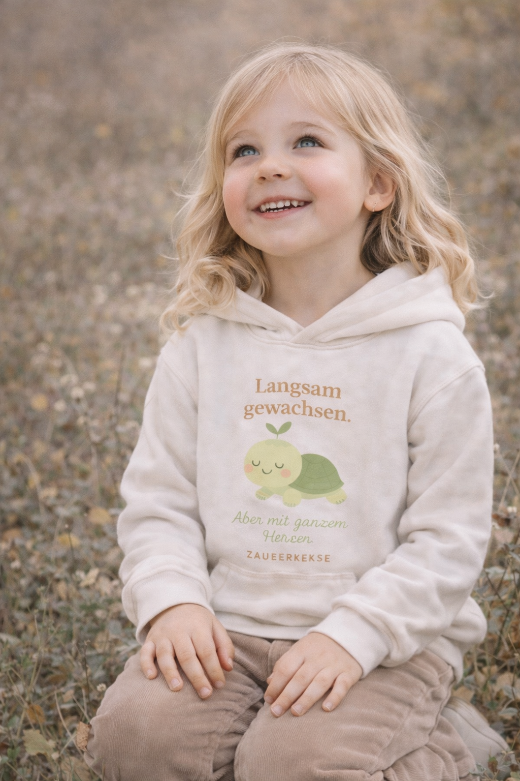 Mädchen trägt cremefarbenen Zauberkekse® Bio Hoodie mit Schneckenmotiv und Text „Langsam gewachsen“ im Scandi-Stil.